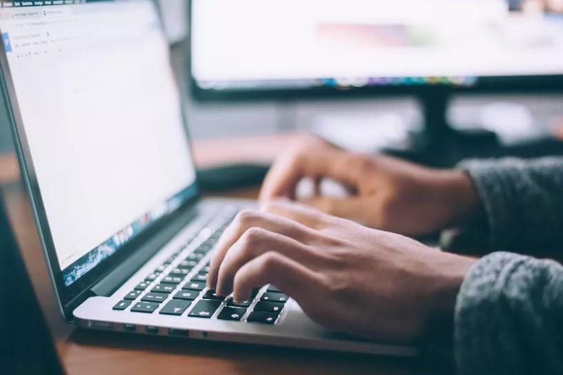 Zwei Hände tippen auf Laptoptastatur