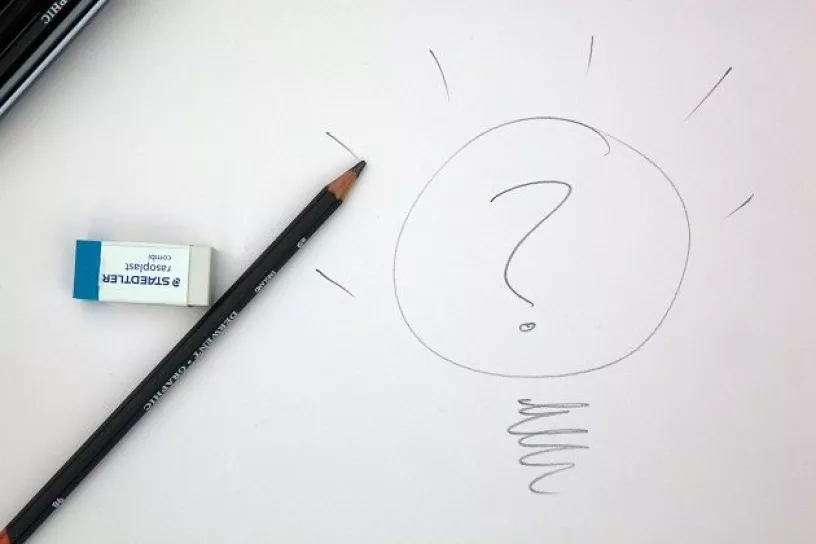 Eine mit Bleistift gezeichnete Glühbirne mit einem Fragezeichen in der Mitte.