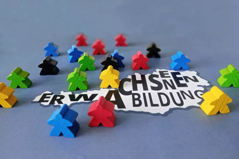 Österreichkarte mit Buchstaben "Erwachsenenbildung" rund herum Spielfiguren