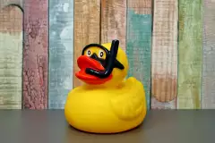 Gummiente mit Taucherbrille vor einem bunten Hintergrund
