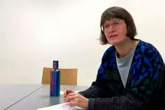 Universitätsprofessorin Doktorin Maria Stimm am Tisch sitzend.